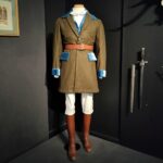 Tenue de chasse à courre composée d'une veste marron à revers turquoise, d'une culotte blanche, d'une ceinture en cuir et de bottes en cuir