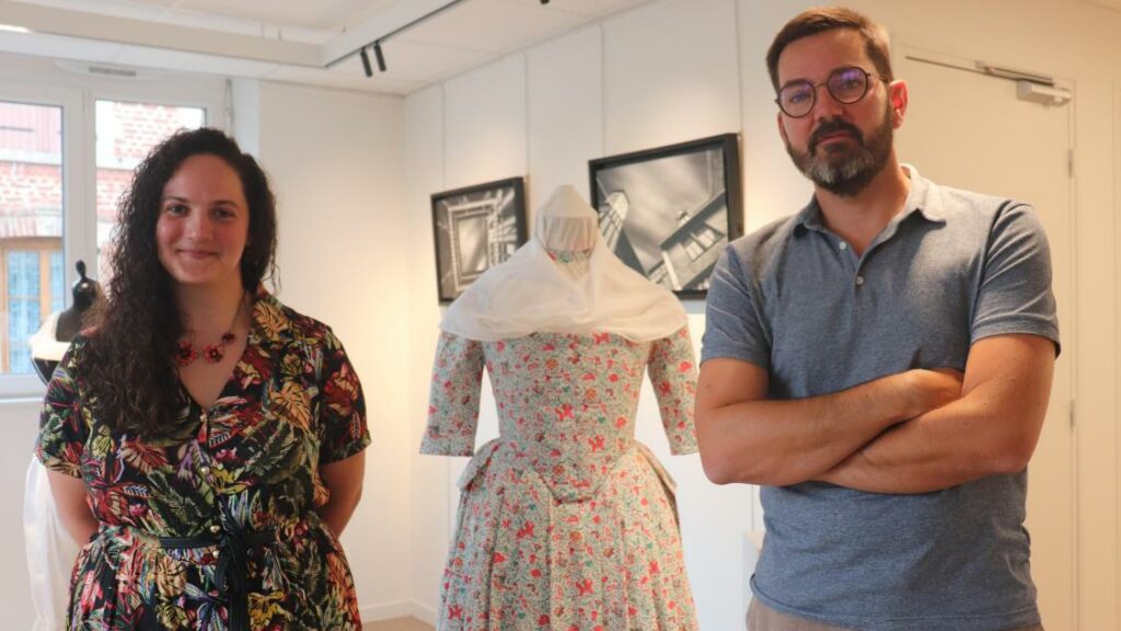 Anaïs Mérat et Benoît Thiérard posent devant un costume et deux photos de l'exposition