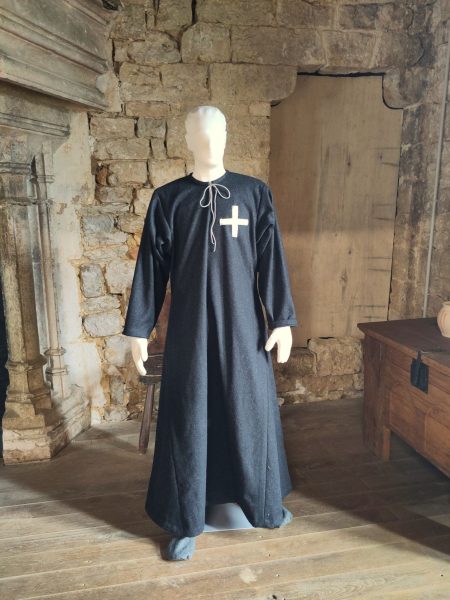 Mannequin habillé d'une tunique longue grise foncée avec une croix blanche sur la poitrine