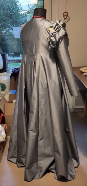 Manteau en soie bleue, vue de trois-quart dos montrant les larges plis dans la partie jupe
