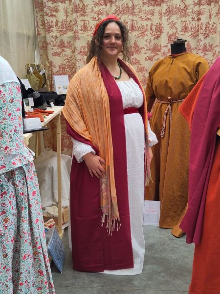 Photo d'Anaïs Mérat portant une robe blanche ceinturée d'un large ruban de velours rouge, avec un châle rouge foncé et un châle orange pâle