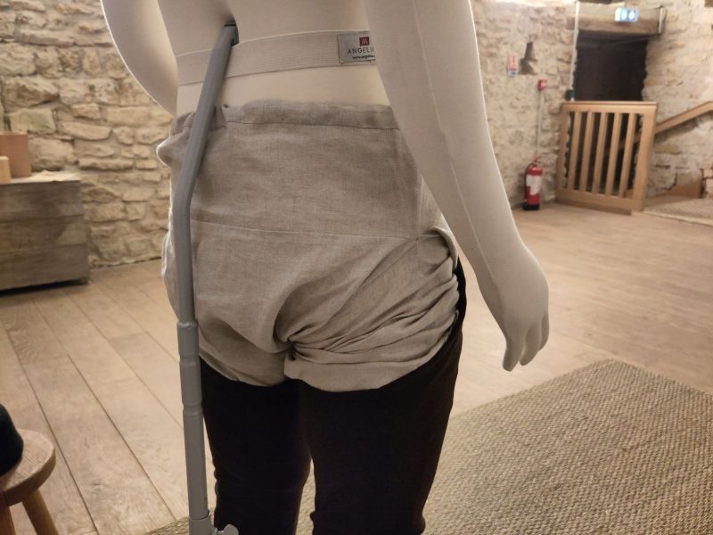 Mannequin habillé d'une sorte de caleçon en lin écru et de chausses en laine marron sur les jambes, vue de dos
