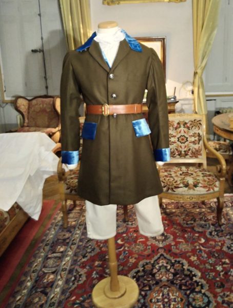 Reconstitution de la tenue de chasse vue de face avec la redingote en lainage marron aux détails en velours turquoise, la culotte blanche et une ceinture en cuir