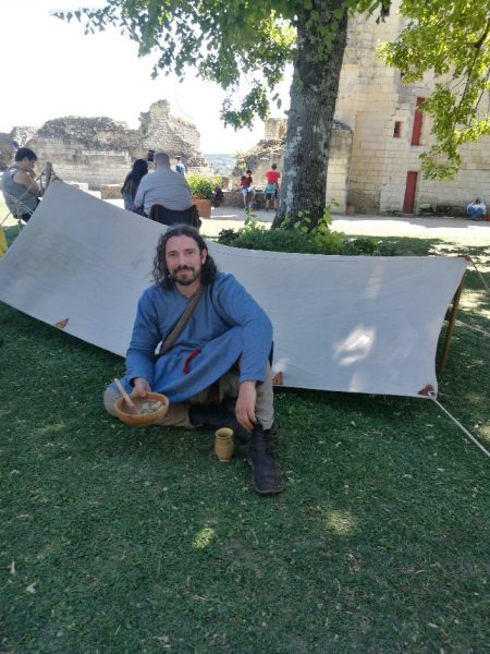 Homme en tunique longue bleue assis devant un avent en tissu